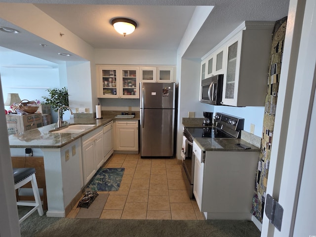 2100 Sea Mountain Hwy Unit 520, North Myrtle Beach, SC 29582 - kitchen featuring appliances with stainless steel finishes, a peninsula, light tile patterned floors, glass insert cabinets, and white cabinetry