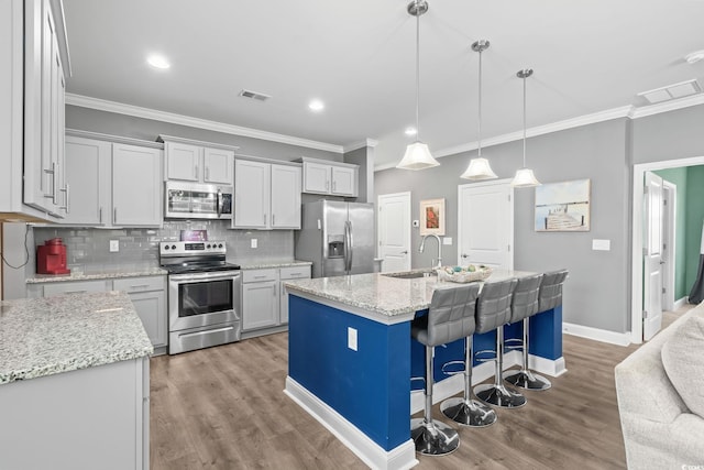 1007 Oak Marsh Ln, North Myrtle Beach, SC 29582 - kitchen featuring stainless steel appliances, ornamental molding, tasteful backsplash, a breakfast bar, and wood finished floors