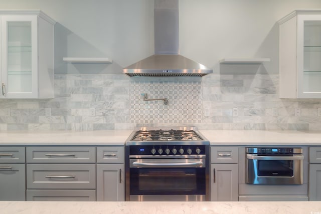 520 Oak Pond Ct, Conway, SC 29526 - kitchen with wall chimney range hood, appliances with stainless steel finishes, gray cabinetry, and glass insert cabinets