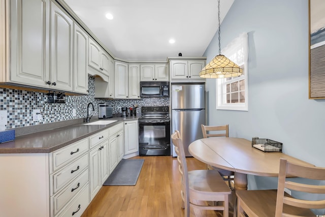 6001-Q21 S Kings Hwy, Myrtle Beach, SC 29575 - kitchen with black appliances, dark countertops, decorative backsplash, light wood-style flooring, and hanging light fixtures