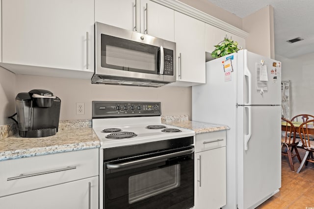 800 9th Ave S Unit N-1, North Myrtle Beach, SC 29582 - kitchen with electric range, stainless steel microwave, freestanding refrigerator, light wood-style floors, and white cabinetry
