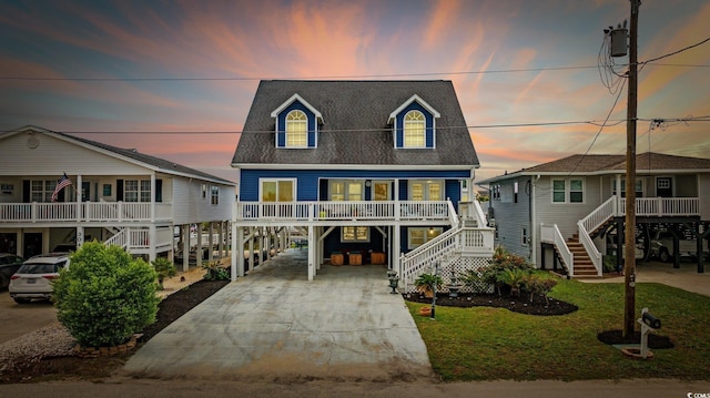 302 46th Ave N, North Myrtle Beach, SC 29582 - coastal home with a carport, stairs, concrete driveway, a porch, and roof with shingles