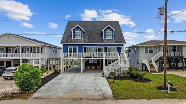 302 46th Ave N, North Myrtle Beach, SC 29582 - raised beach house featuring a carport, stairway, concrete driveway, covered porch, and a front lawn
