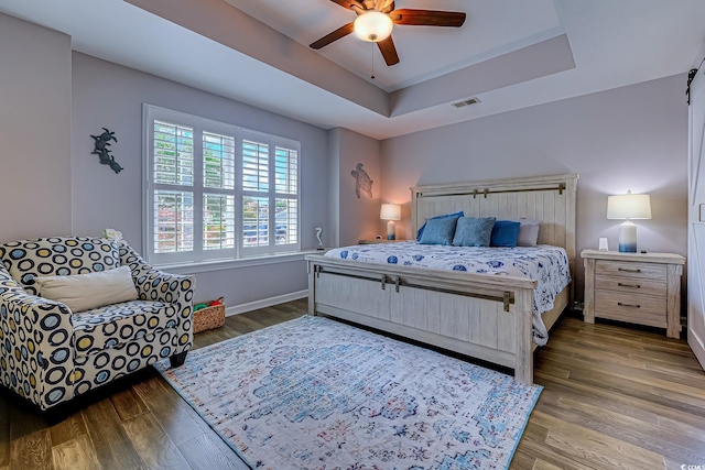 2479 Burning Tree Ln, Little River, SC 29566 - bedroom featuring a raised ceiling, wood finished floors, and a ceiling fan