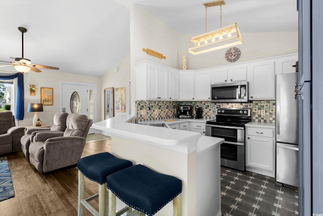 1644 Langley Dr, Longs, SC 29568 - kitchen featuring appliances with stainless steel finishes, open floor plan, a peninsula, white cabinetry, and high vaulted ceiling