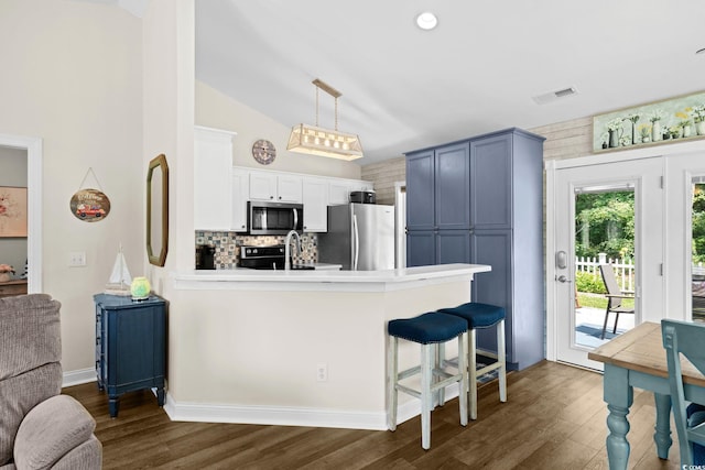 1644 Langley Dr, Longs, SC 29568 - kitchen featuring appliances with stainless steel finishes, a peninsula, dark wood-style flooring, a kitchen bar, and vaulted ceiling