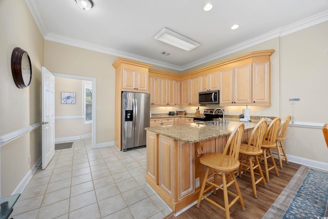 139 Avian Dr Unit 6-201, Pawleys Island, SC 29585 - kitchen with appliances with stainless steel finishes, a peninsula, light brown cabinetry, light stone counters, and crown molding
