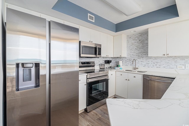8560 Queensway Blvd Unit 706, Myrtle Beach, SC 29572 - kitchen featuring appliances with stainless steel finishes, backsplash, white cabinetry, and light wood-style flooring