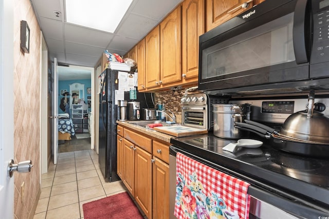 6804 N Ocean Blvd Unit 515, Myrtle Beach, SC 29572 - kitchen featuring black appliances, light tile patterned floors, light countertops, brown cabinetry, and decorative backsplash