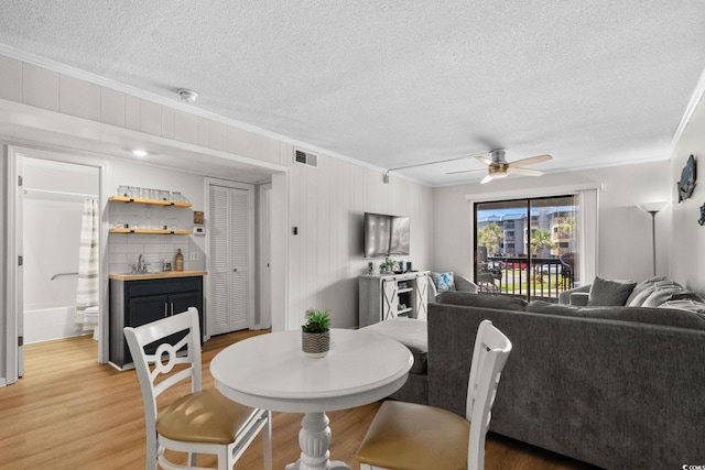 6001 N Ocean Blvd Unit 137, North Myrtle Beach, SC 29582 - dining space with crown molding, a textured ceiling, ceiling fan, and light wood-style flooring