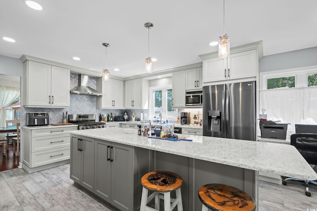 528 George Washington Trl, Georgetown, SC 29440 - kitchen featuring appliances with stainless steel finishes, wall chimney range hood, backsplash, gray cabinetry, and light stone counters
