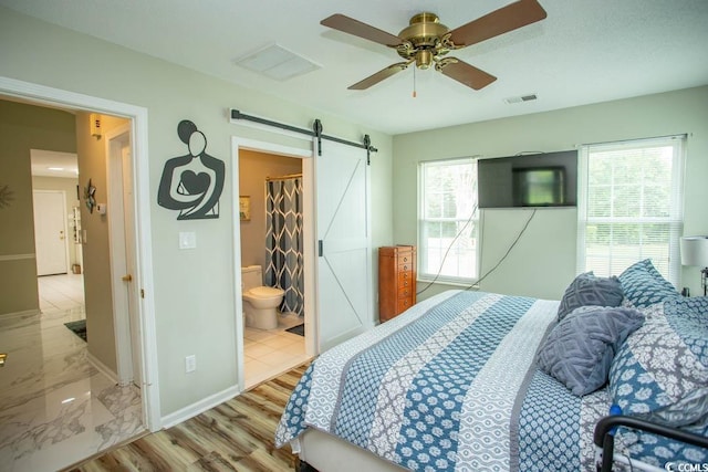 654 Blue Bird Ln, Murrells Inlet, SC 29576 - bedroom with a barn door, ceiling fan, and connected bathroom
