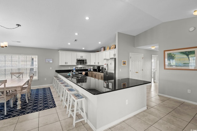 221 N Waccamaw Dr, Murrells Inlet, SC 29576 - kitchen featuring stainless steel appliances, light tile patterned flooring, dark countertops, vaulted ceiling, and white cabinets