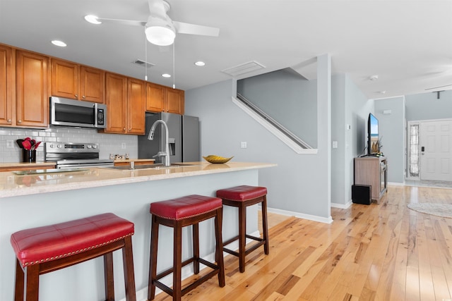 864 Barn Owl Ct Unit 864, Myrtle Beach, SC 29579 - kitchen featuring stainless steel appliances, a breakfast bar, decorative backsplash, brown cabinets, and a ceiling fan