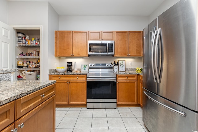 70 Addison Cottage Way Unit 216, Murrells Inlet, SC 29576 - kitchen with stainless steel appliances, light tile patterned floors, brown cabinets, and light stone counters
