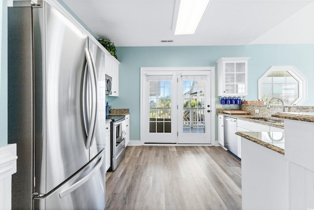 204 24th Ave N, North Myrtle Beach, SC 29582 - kitchen featuring appliances with stainless steel finishes, white cabinetry, light wood finished floors, light stone countertops, and glass insert cabinets
