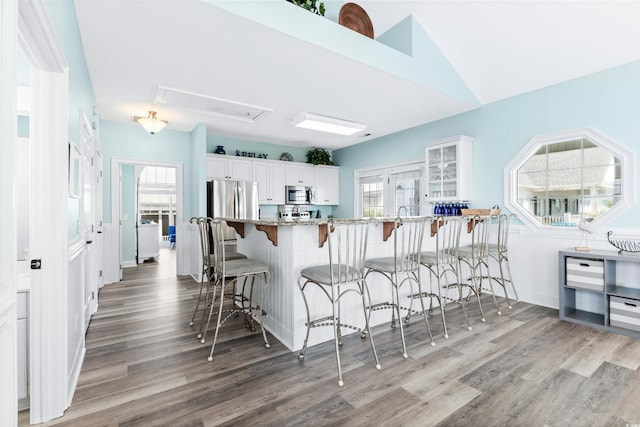 204 24th Ave N, North Myrtle Beach, SC 29582 - kitchen with appliances with stainless steel finishes, a kitchen bar, wood finished floors, and light stone counters