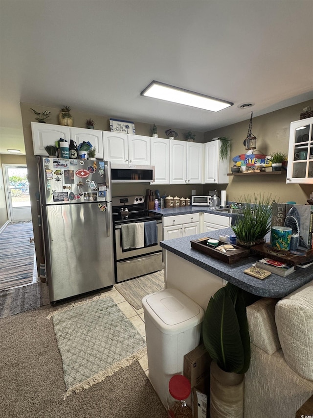 1851 Colony Dr Unit 5M, Surfside Beach, SC 29575 - kitchen with stainless steel appliances, dark countertops, white cabinetry, a kitchen breakfast bar, and a peninsula