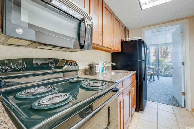 1105 S Ocean Blvd Unit 128, Myrtle Beach, SC 29577 - kitchen with black appliances, brown cabinetry, light stone counters, light colored carpet, and light tile patterned floors