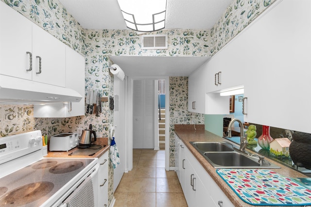 500 Eagle Way Unit 19, Little River, SC 29566 - kitchen with electric range, under cabinet range hood, wallpapered walls, white cabinetry, and light tile patterned flooring