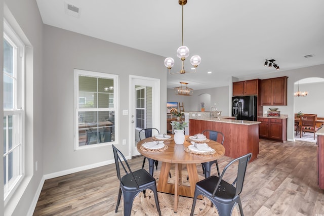 1276 Brighton Hill Ave, Myrtle Beach, SC 29588 - dining area featuring a chandelier, wood finished floors, plenty of natural light, and arched walkways