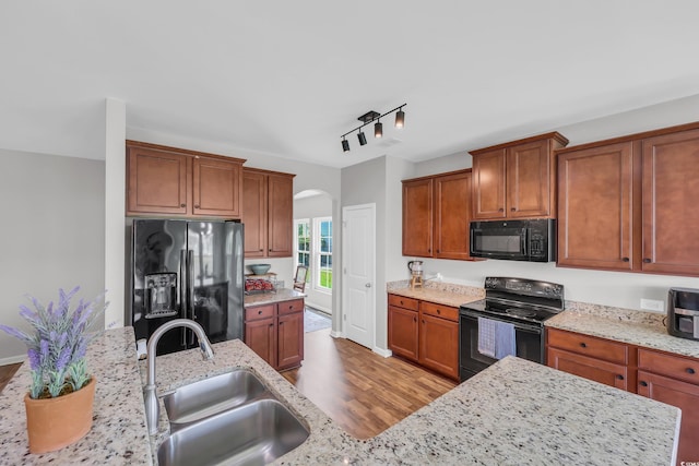 1276 Brighton Hill Ave, Myrtle Beach, SC 29588 - kitchen with black appliances, arched walkways, wood finished floors, light stone countertops, and brown cabinets