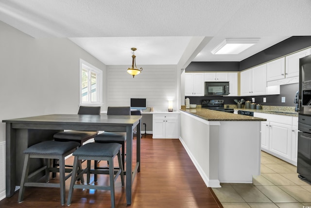 10301 N Kings Hwy Unit 21-4, Myrtle Beach, SC 29572 - kitchen with black appliances, white cabinets, a peninsula, a textured ceiling, and dark stone countertops
