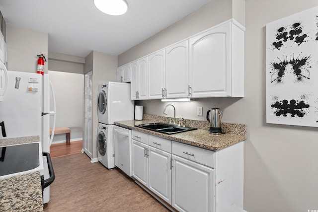 400 20th Ave N Unit 606, Myrtle Beach, SC 29577 - kitchen with estacked washer and dryer, white appliances, white cabinetry, and light wood-type flooring