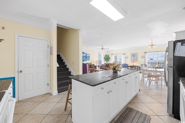 817 S Ocean Blvd Unit 201, North Myrtle Beach, SC 29582 - kitchen with freestanding refrigerator, ornamental molding, light tile patterned floors, a kitchen island, and white cabinetry
