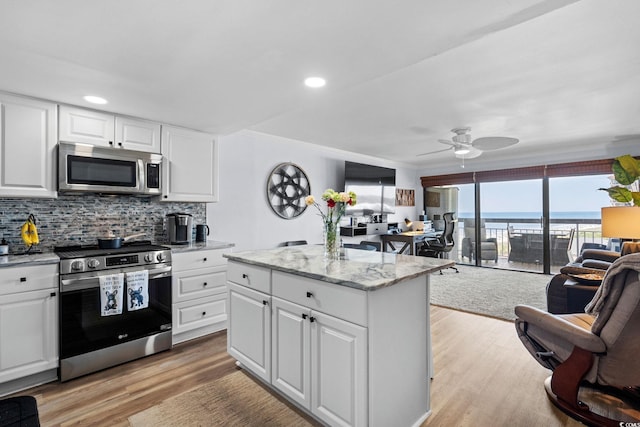 5511 N Ocean Blvd Unit 902, Myrtle Beach, SC 29577 - kitchen featuring appliances with stainless steel finishes, open floor plan, light wood finished floors, decorative backsplash, and a ceiling fan