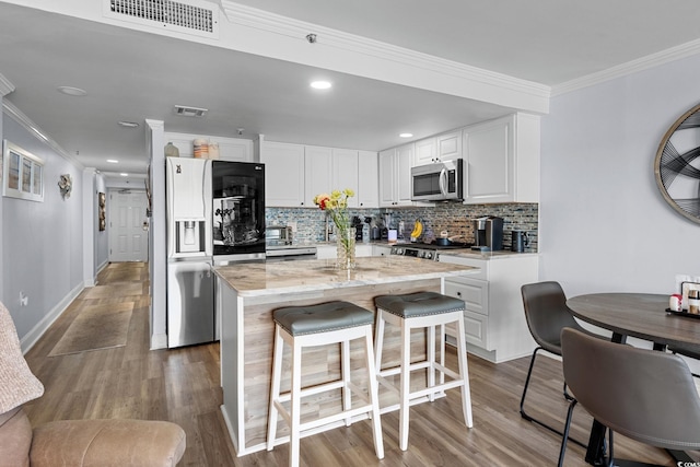 5511 N Ocean Blvd Unit 902, Myrtle Beach, SC 29577 - kitchen with stainless steel appliances, ornamental molding, backsplash, white cabinetry, and wood finished floors