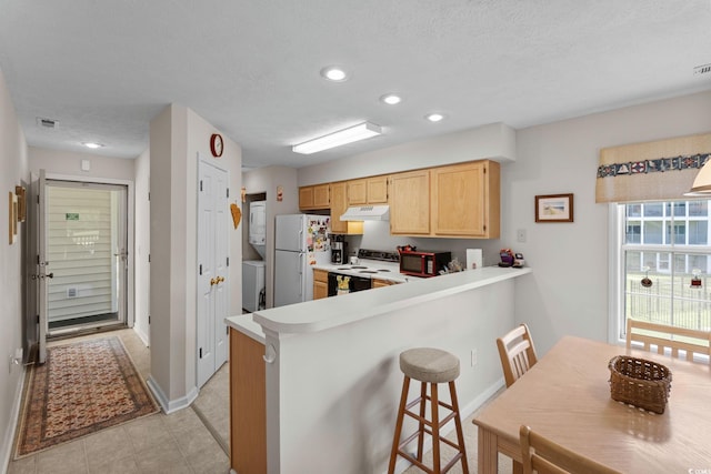 493 White River Dr Unit 28-D, Myrtle Beach, SC 29579 - kitchen with range with electric stovetop, estacked washer and dryer, light brown cabinets, freestanding refrigerator, and under cabinet range hood