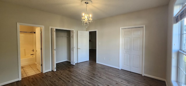 134 Scotch Broom Dr Unit K-203, Little River, SC 29566 - unfurnished bedroom with multiple closets, a chandelier, dark wood-style flooring, and ensuite bathroom