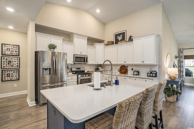 860 Brant St, Myrtle Beach, SC 29579 - kitchen featuring appliances with stainless steel finishes, wood finished floors, white cabinets, a center island with sink, and high vaulted ceiling