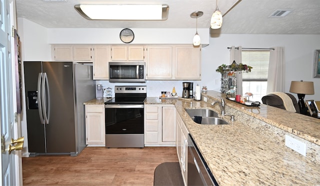 697 Tupelo Ln Unit 24G, Longs, SC 29568 - kitchen with stainless steel appliances, light wood-style flooring, light stone countertops, hanging light fixtures, and a textured ceiling