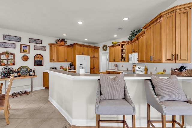 4507 Smilax Pl, Murrells Inlet, SC 29576 - kitchen with white appliances, a kitchen breakfast bar, a peninsula, recessed lighting, and brown cabinetry