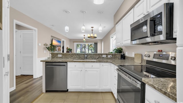 521 White River Dr Unit 21C, Myrtle Beach, SC 29579 - kitchen with appliances with stainless steel finishes, a peninsula, white cabinetry, and stone countertops