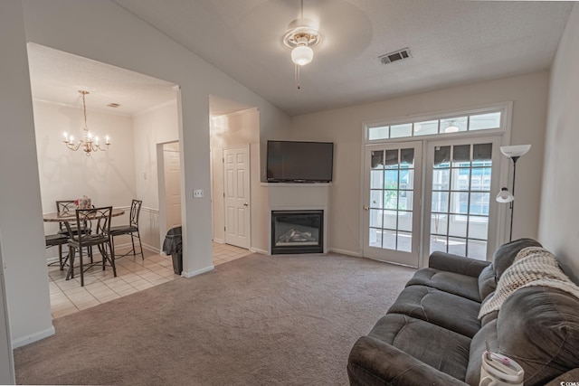 9755 Leyland Dr Unit 11, Myrtle Beach, SC 29572 - carpeted living room featuring a chandelier, ceiling fan, a glass covered fireplace, vaulted ceiling, and tile patterned flooring