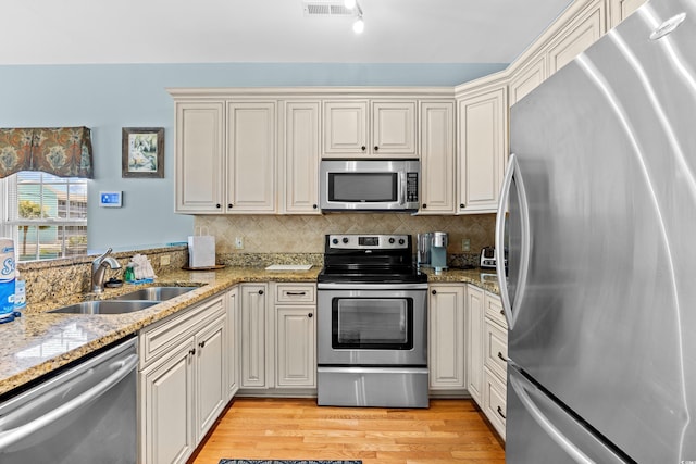 1020 Ocean Blvd S Unit A, Surfside Beach, SC 29575 - kitchen featuring appliances with stainless steel finishes, light wood-type flooring, decorative backsplash, light stone countertops, and a peninsula