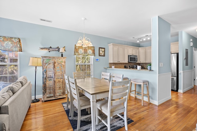 1020 Ocean Blvd S Unit A, Surfside Beach, SC 29575 - dining space featuring light wood finished floors, a chandelier, and wainscoting