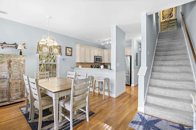 1020 Ocean Blvd S Unit A, Surfside Beach, SC 29575 - dining area featuring stairs, light wood-style floors, and a chandelier