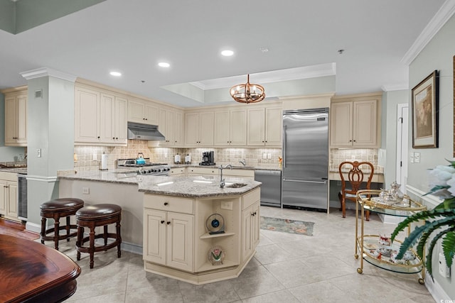 9547 Edgerton Dr Unit 405, Myrtle Beach, SC 29572 - kitchen featuring cream cabinetry, appliances with stainless steel finishes, under cabinet range hood, crown molding, and light stone countertops