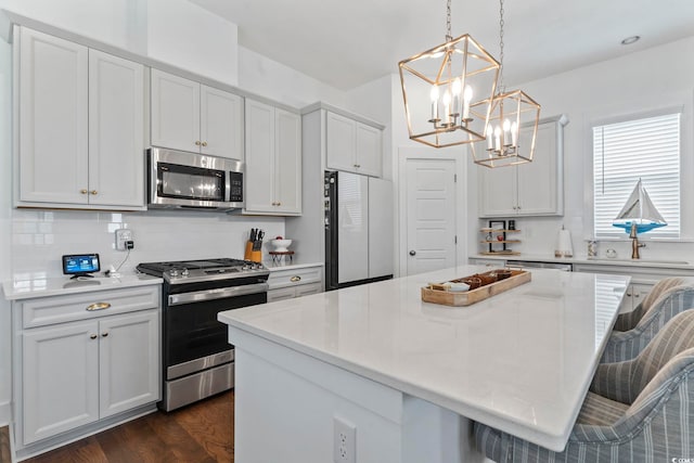 1524 Sayebrook Pkwy, Myrtle Beach, SC 29588 - kitchen featuring stainless steel appliances, a chandelier, a kitchen island, dark wood-style flooring, and a kitchen breakfast bar