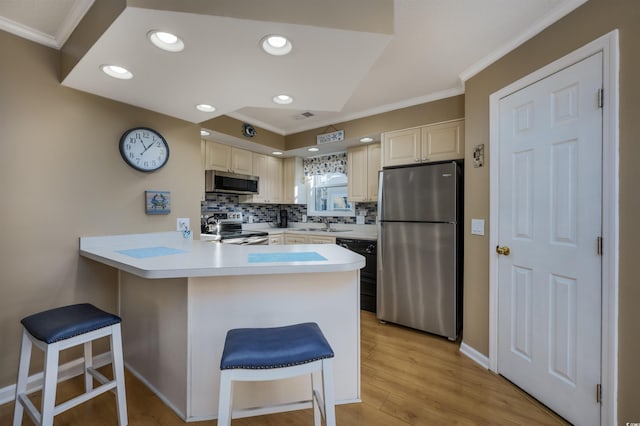 300 Shorehaven Dr Unit I-2, North Myrtle Beach, SC 29582 - kitchen featuring appliances with stainless steel finishes, ornamental molding, a peninsula, a breakfast bar area, and tasteful backsplash