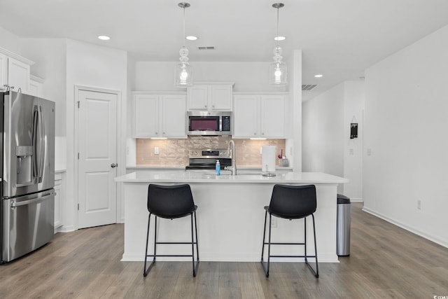 219 Glenmoor Dr, Conway, SC 29526 - kitchen with appliances with stainless steel finishes, wood finished floors, decorative backsplash, light countertops, and white cabinets