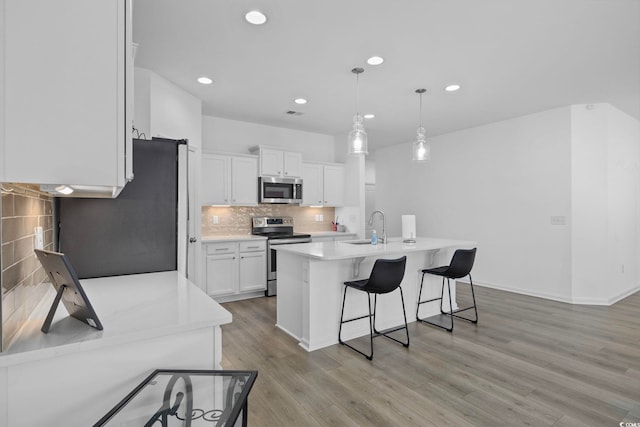 219 Glenmoor Dr, Conway, SC 29526 - kitchen featuring appliances with stainless steel finishes, a breakfast bar area, white cabinetry, tasteful backsplash, and light countertops