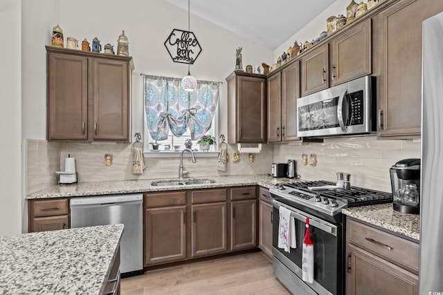 2781 Desert Rose St, Little River, SC 29566 - kitchen featuring appliances with stainless steel finishes, vaulted ceiling, light stone countertops, light wood-style flooring, and decorative backsplash