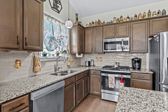 2781 Desert Rose St, Little River, SC 29566 - kitchen featuring appliances with stainless steel finishes, light stone countertops, decorative backsplash, light wood-type flooring, and decorative light fixtures