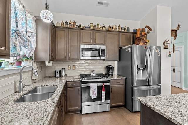 2781 Desert Rose St, Little River, SC 29566 - kitchen featuring appliances with stainless steel finishes, light stone counters, tasteful backsplash, light wood-type flooring, and pendant lighting