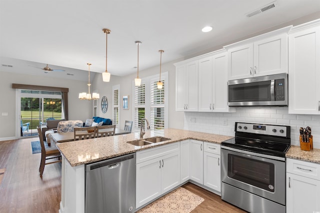 5304 Sea Coral Way N, Myrtle Beach, SC 29582 - kitchen with appliances with stainless steel finishes, a peninsula, light wood-style flooring, white cabinets, and backsplash